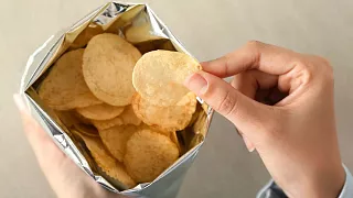 Une personne sort une chips du sac.
