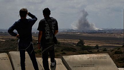 Des personnes regardent la fumée s'élever dans le ciel après une explosion dans la bande de Gaza alors qu'elles visitent un site touristique à Sderot, dans le sud d'Israël, le jeudi 22 mai 2025.